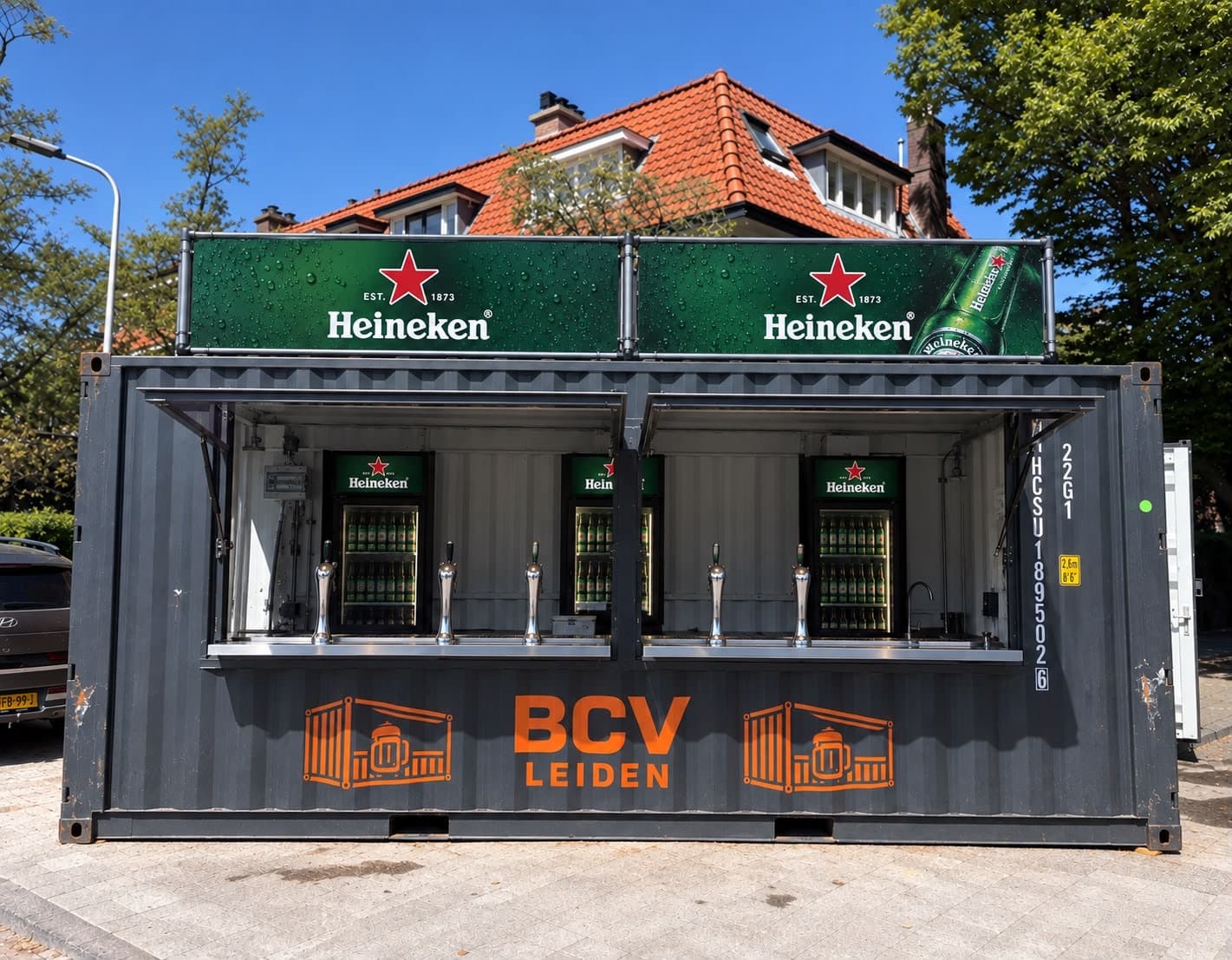 BCV-barcontainer met Heineken-branding op de dakborden en koelkasten en het oranje BCV-logo op de gevel