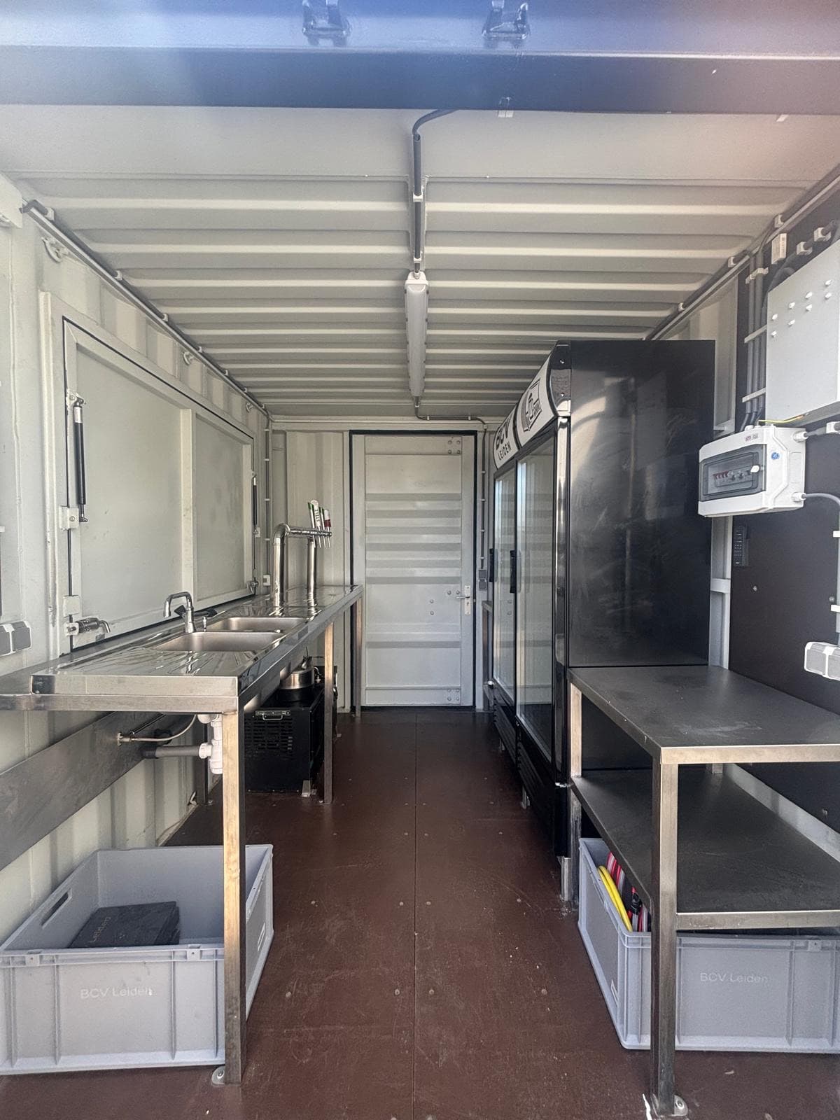 Interieur van de 20 ft barcontainer met spoelbak, werktafels, koelkasten en opbergbakken